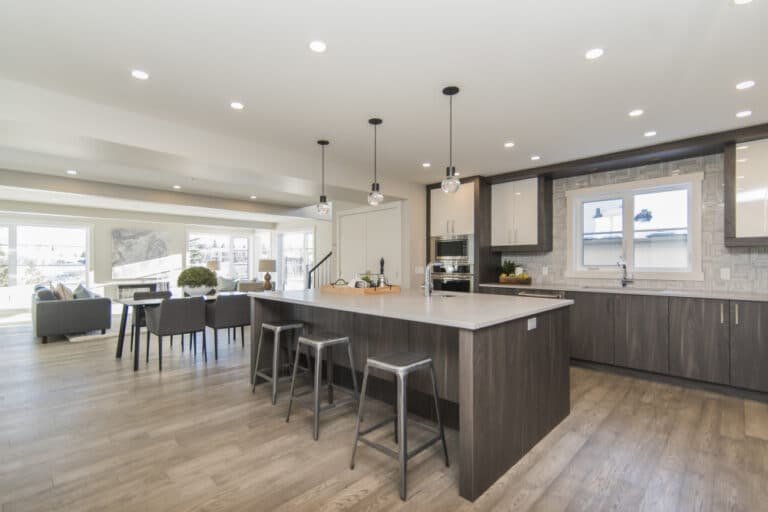 Cuisine ouverte moderne avec îlot central, tabourets et espace salle à manger intégré, donnant sur un salon lumineux.