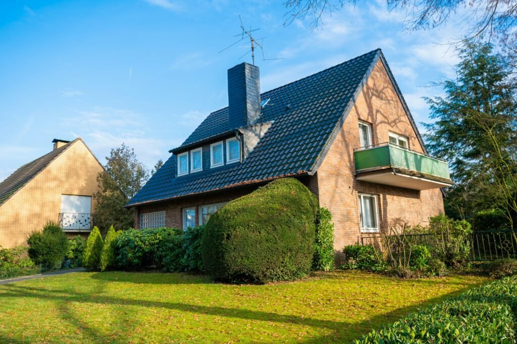 Maison familiale en brique avec jardin bien entretenu sous un ciel bleu clair.