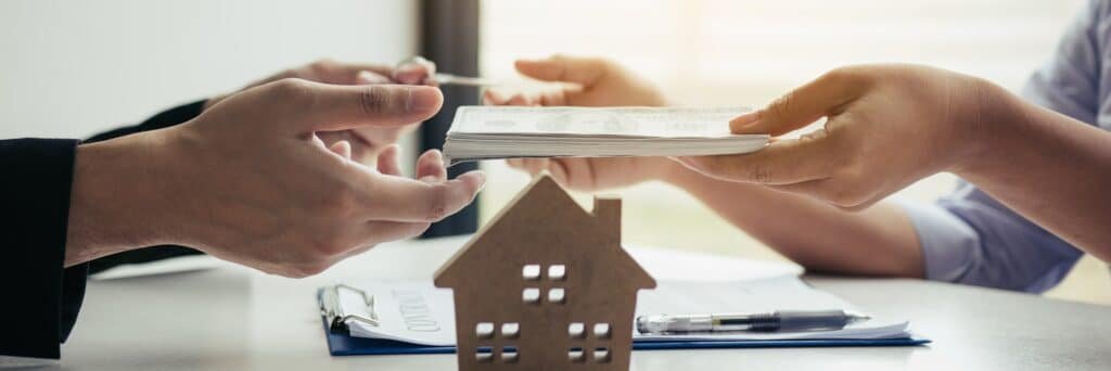 Deux personnes lors d'un accord immobilier avec une petite maquette de maison sur la table.